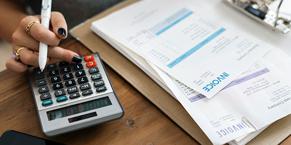 Invoice sitting on desk while woman calculates numbers on calculator