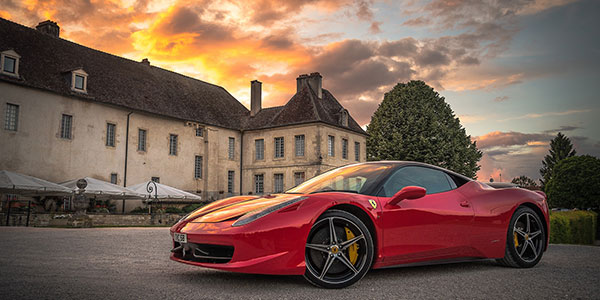 Fancy red sports car in front of very large home
