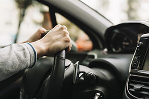 Person driving car with hands on wheel