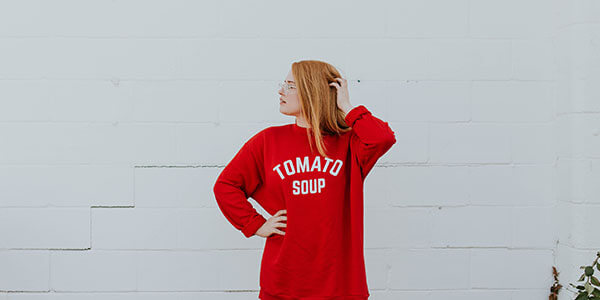 Girl with red hair wearing sweatshirt that says Tomato Soup