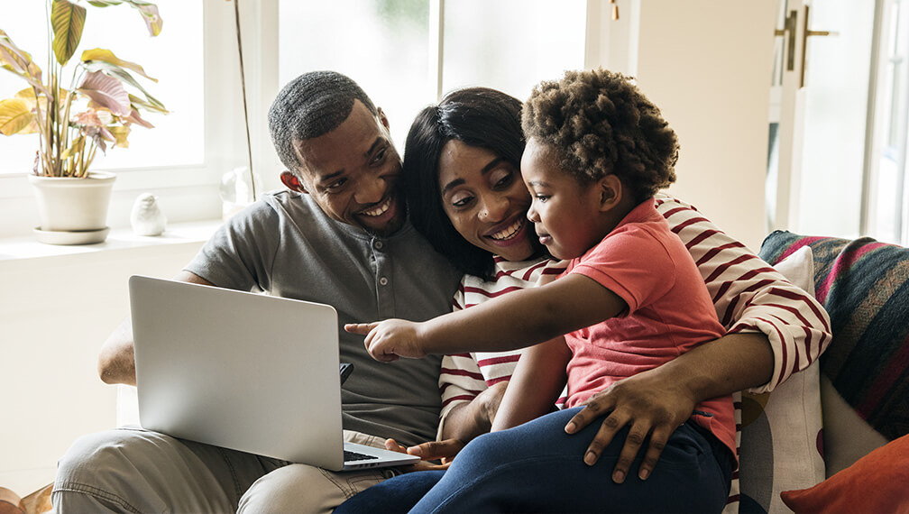 Family of three smiling and looking at computer
