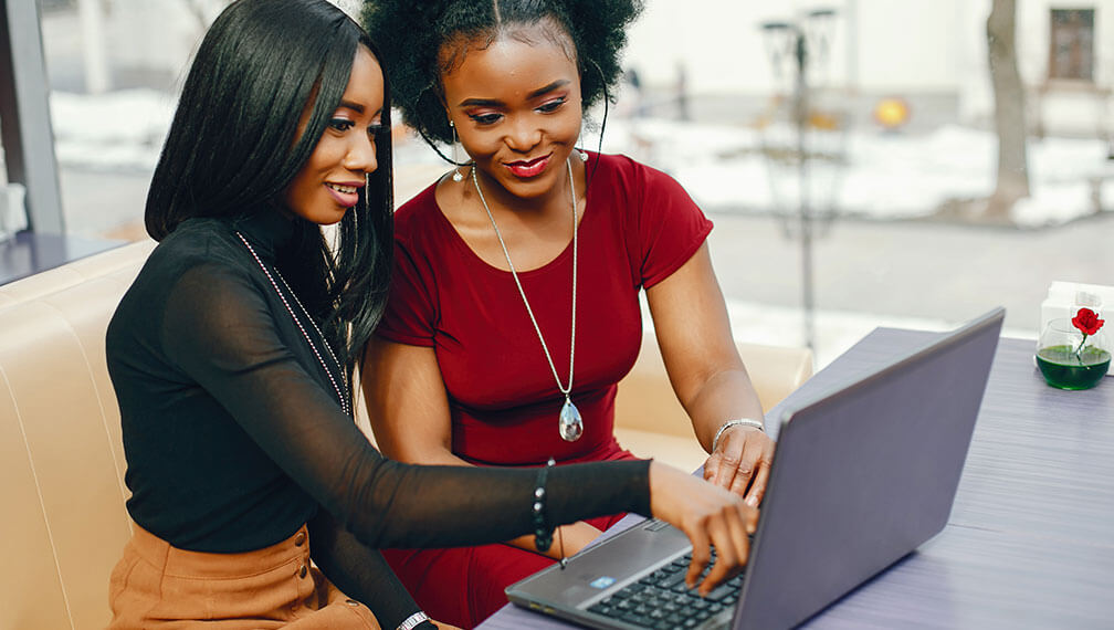 Two friends helping eachother on laptop