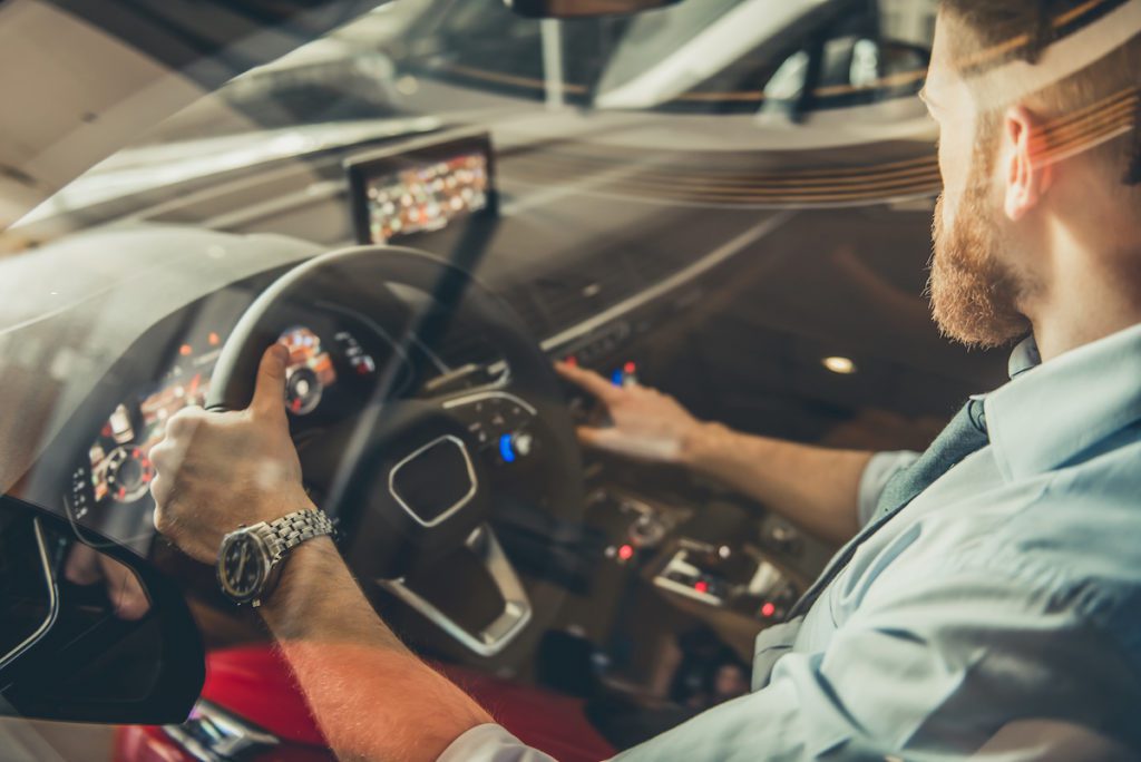 Handsome bearded businessman is sitting in a new car in car dealership