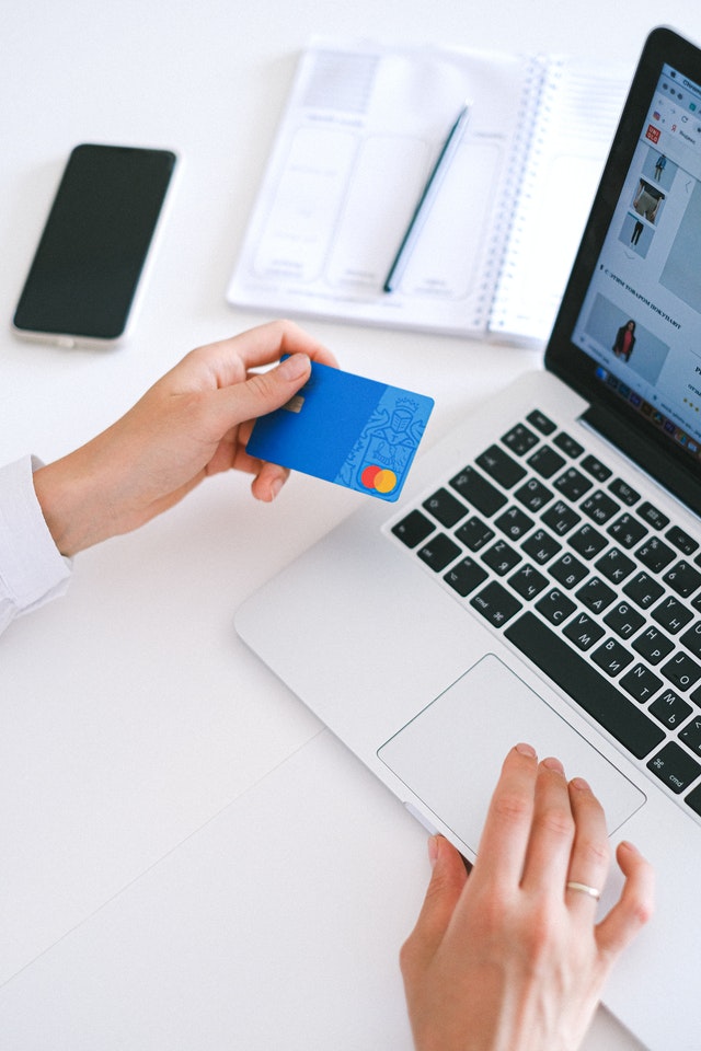 woman holding a credit card and typing on her laptop