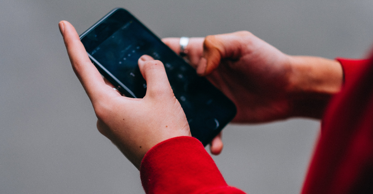 person with red sweatshirt holding a smartphone