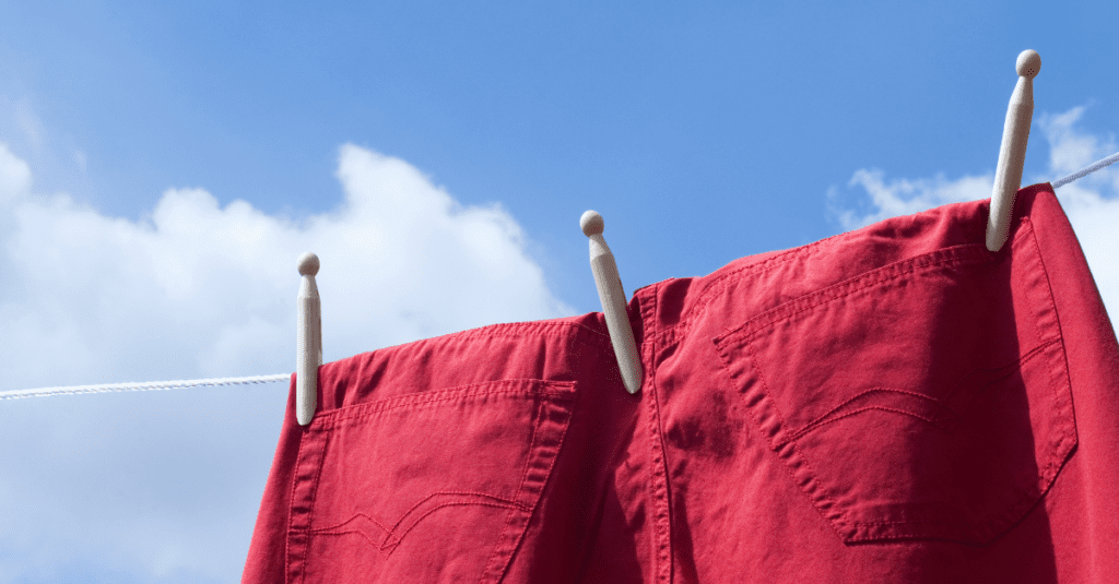 red jean pants on a clothes line blue sky and clouds