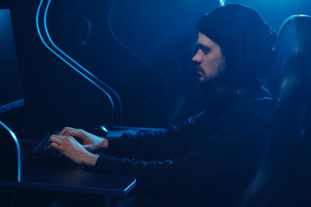 dark room with a person all in black at a computer