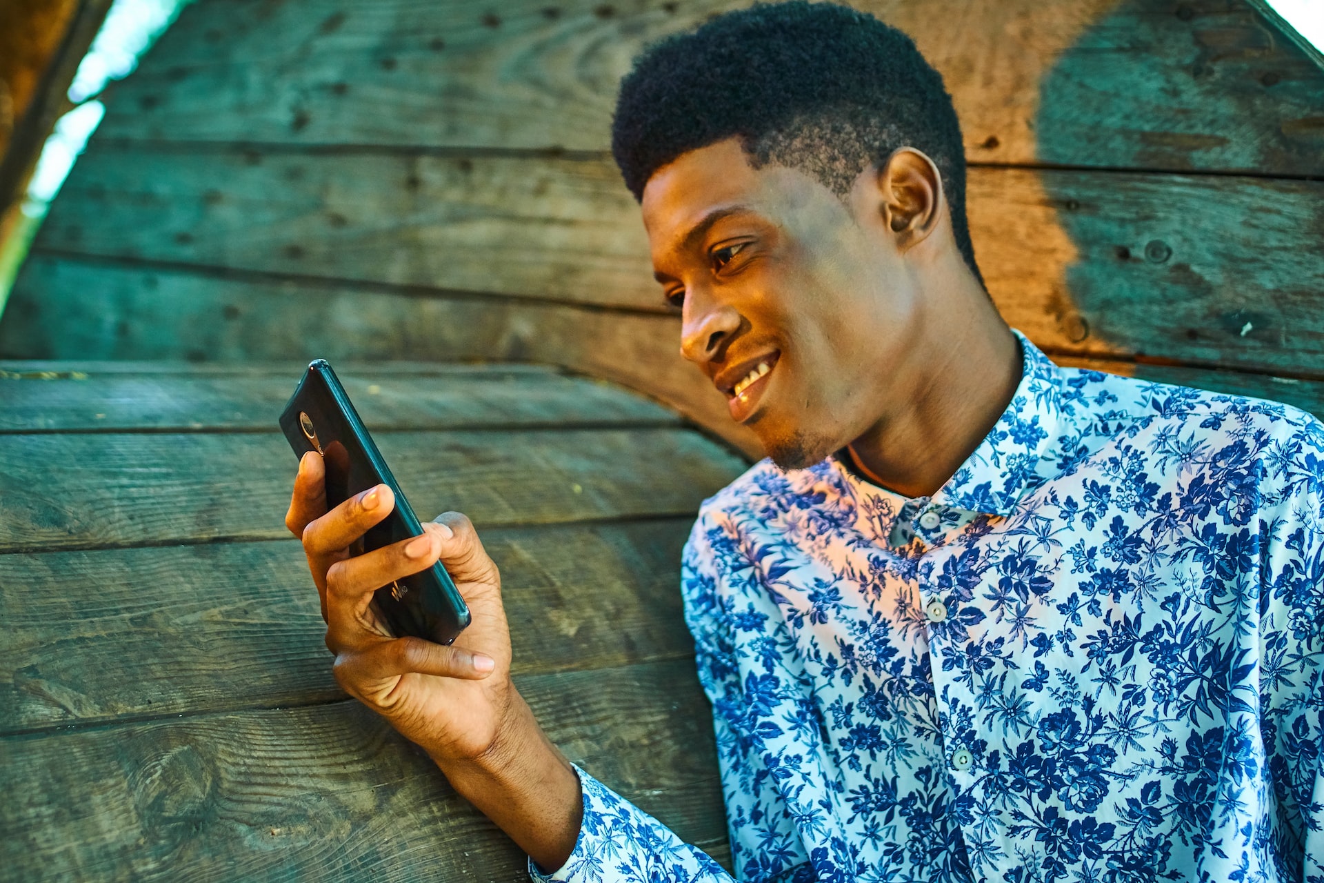 man texting in front of wooden background