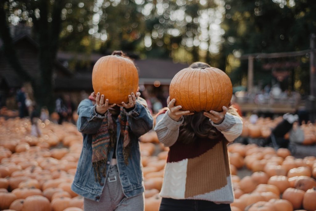 people holding pumpkins in front of their faces