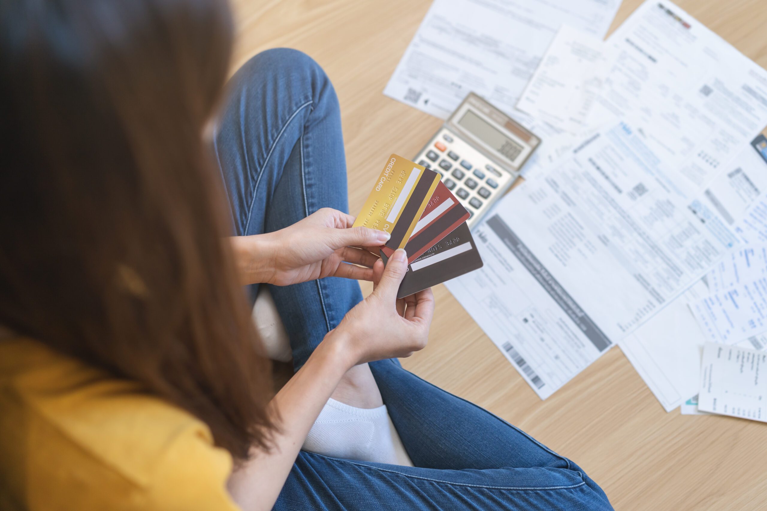 Financial people, owe asian woman, girl sitting on floor at home, hand holding credit card and bills, stressed by calculate expense, no money to pay, mortgage or loan. Debt, bankruptcy or bankrupt.